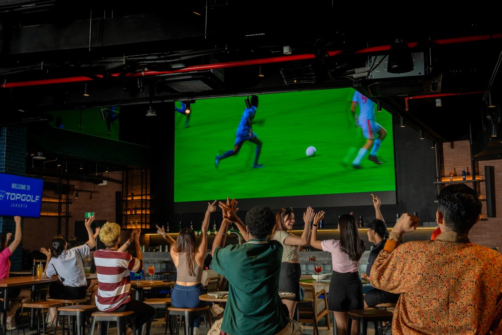 Guests watching a live sports game together at the Topgolf bar
